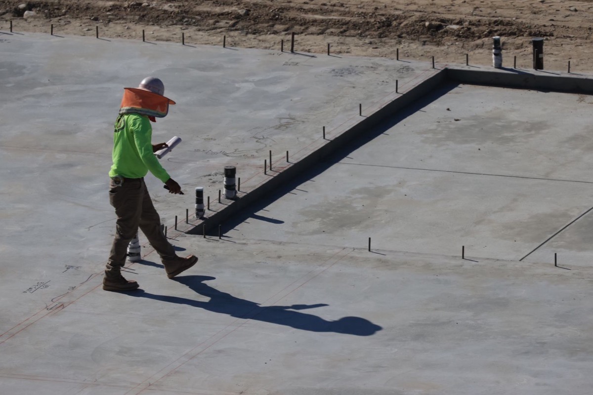 Site engineer walking across a newly placed concrete slab before flooring is installed